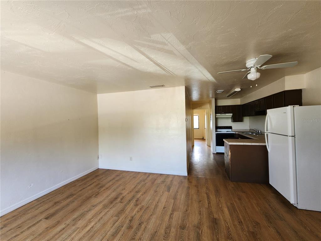 An open living area with wood-look flooring leads to a kitchen with dark cabinets — 719 SW 70TH TERRACE UNIT 5, GAINESVILLE, FL