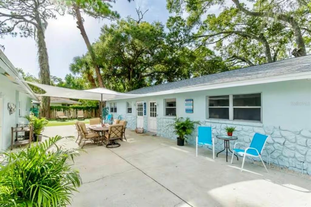 A light blue house exterior features a concrete patio with outdoor furniture and shade sails — 1317 COCOANUT STREET UNIT B, SARASOTA, FL