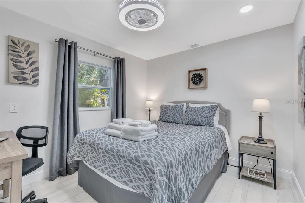 A bedroom features a bed with patterned bedding, a desk, and a bedside table — 1317 COCOANUT STREET UNIT B, SARASOTA, FL