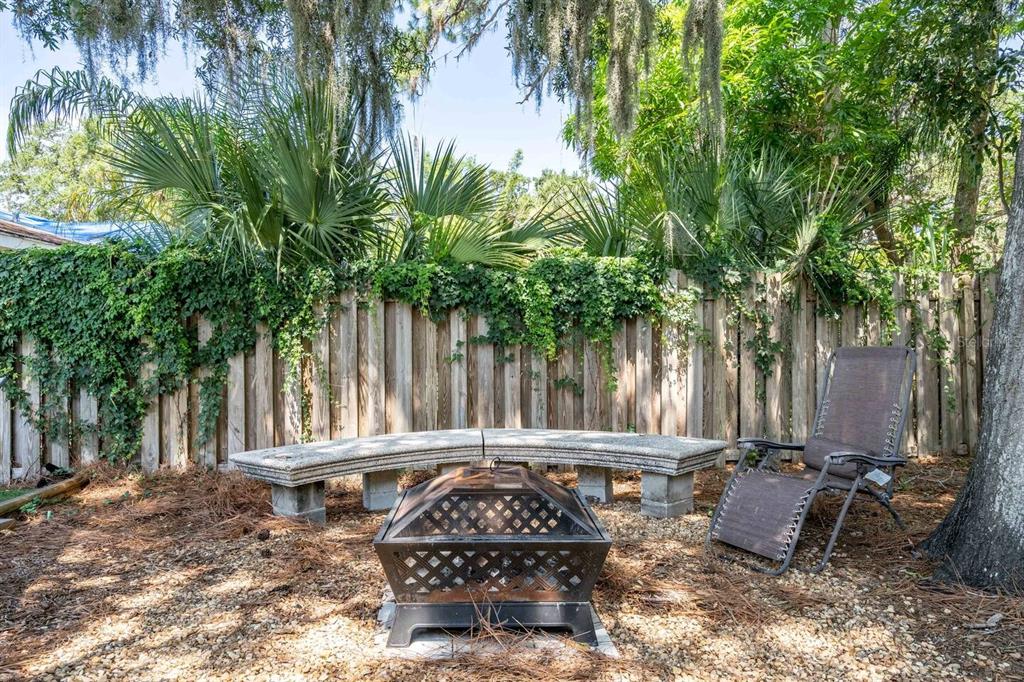 A backyard features a metal fire pit, a curved stone bench, and a lounge chair — 1317 COCOANUT STREET UNIT B, SARASOTA, FL