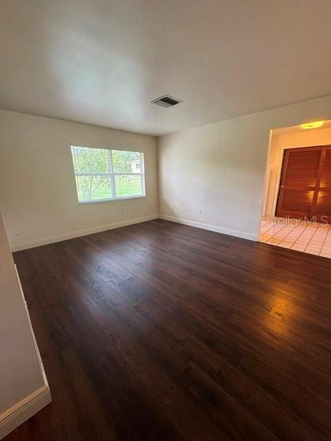 An empty room features dark wood-look flooring, light-colored walls, and a window — 37623 CAMPHOR DRIVE, DADE CITY, FL