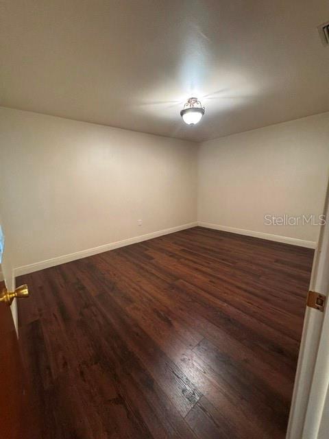 An empty bedroom features dark wood-look flooring, light-colored walls, and a ceiling light fixture — 37623 CAMPHOR DRIVE, DADE CITY, FL