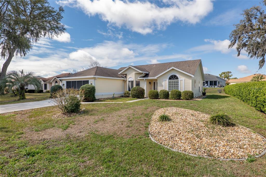 A yellow, single-story suburban house with a driveway, a landscaped yard, and a gravel bed — 2318 NW 50TH AVENUE, OCALA, FL