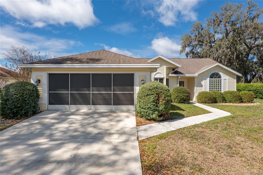 A single-story house with yellow siding, a screened garage door, and a concrete driveway — 2318 NW 50TH AVENUE, OCALA, FL