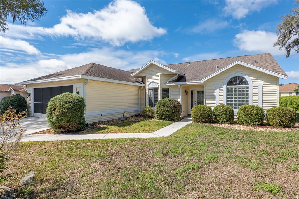 A yellow single-story house with a garage and a front walkway under a blue sky — 2318 NW 50TH AVENUE, OCALA, FL
