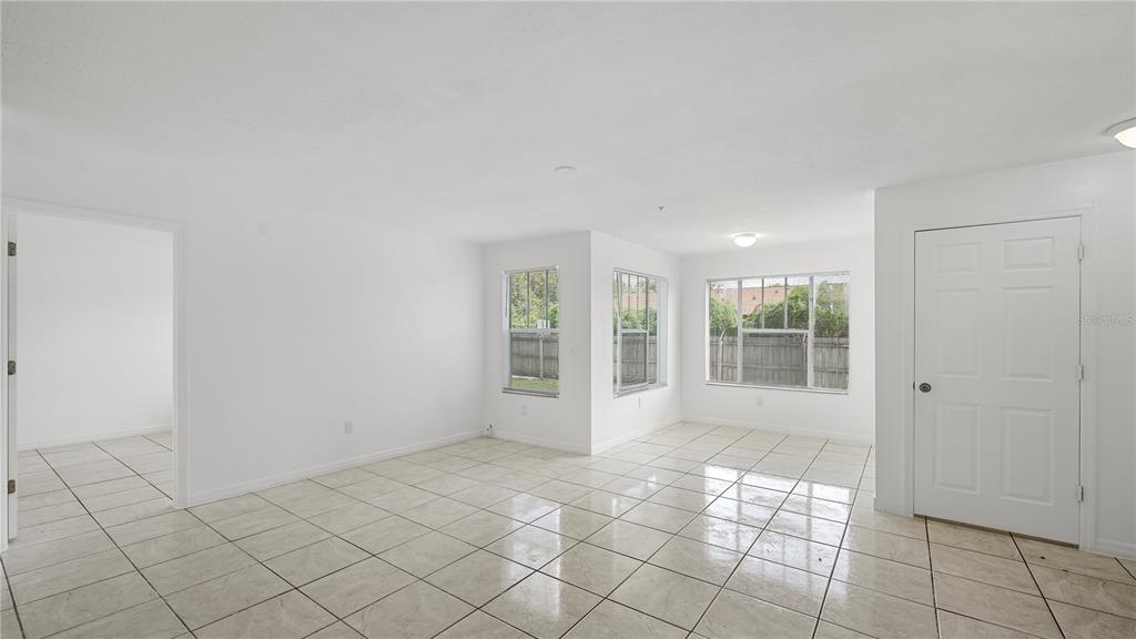 An empty room with white walls, tiled floors, and multiple windows overlooking a wooden fence — 2204 KEY WEST COURT UNIT 518, KISSIMMEE, FL