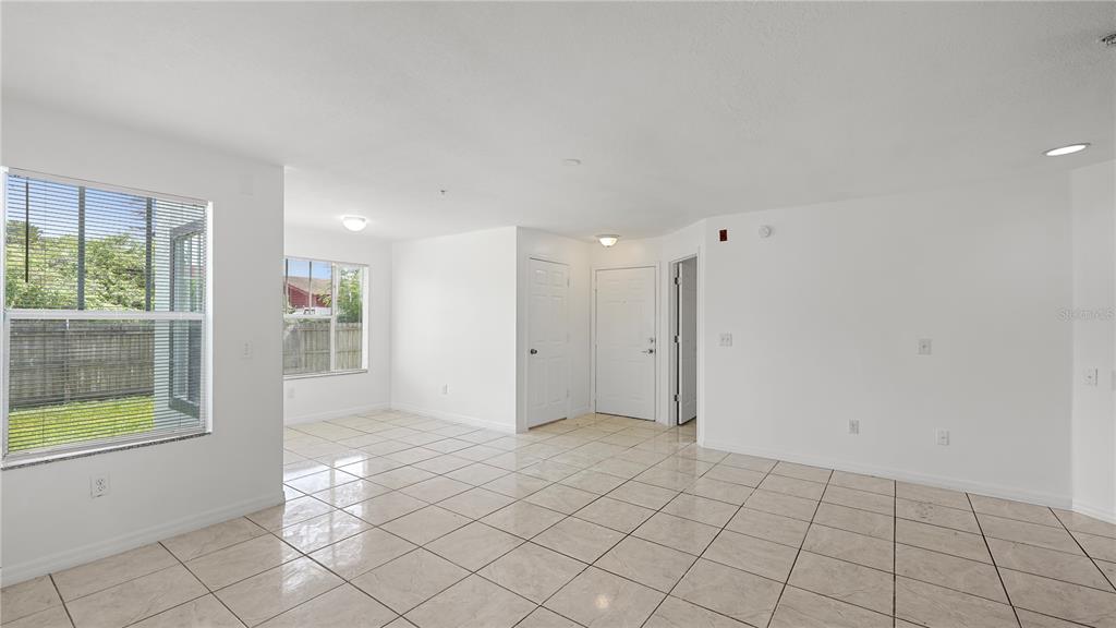 An empty room with white walls, tiled floors, and two windows looking out onto grass — 2204 KEY WEST COURT UNIT 518, KISSIMMEE, FL