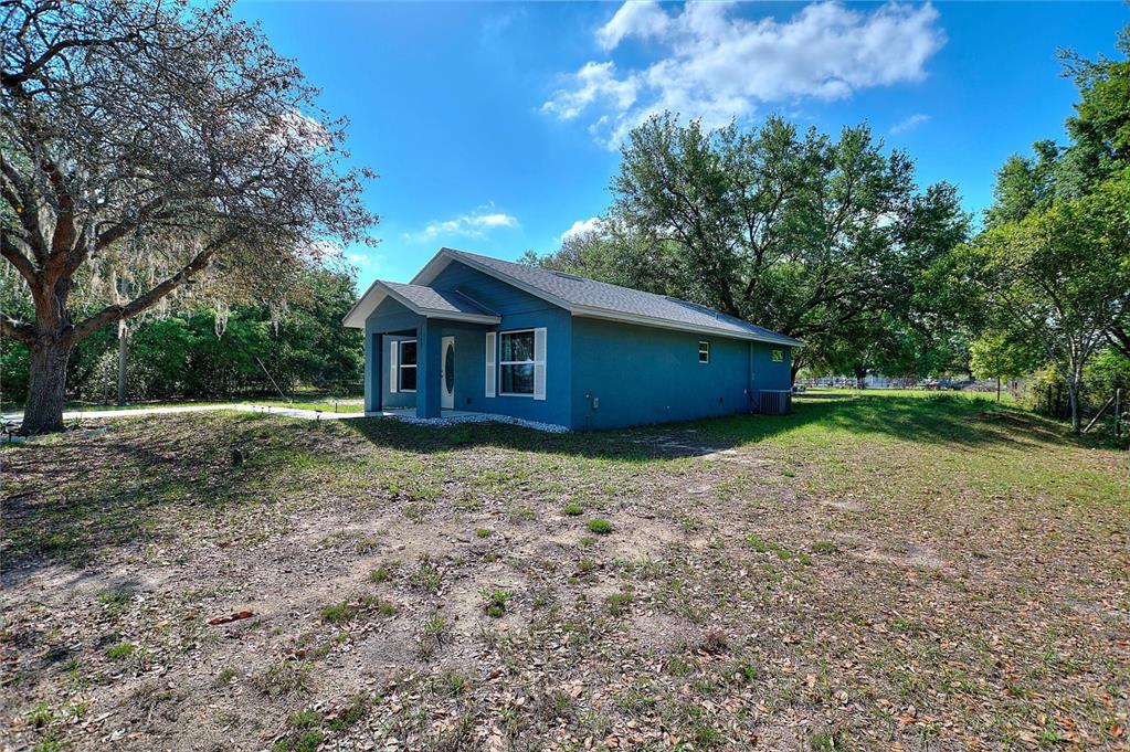 A blue single-story house with a covered porch sits on a large, grassy lot — 3443 COUNTY ROAD 557A, POLK CITY, FL