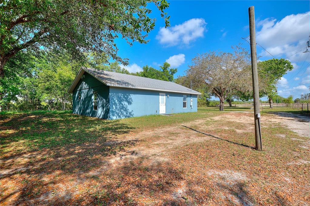 A blue single-story house sits on a grassy lot with a utility pole nearby — 3443 COUNTY ROAD 557A, POLK CITY, FL