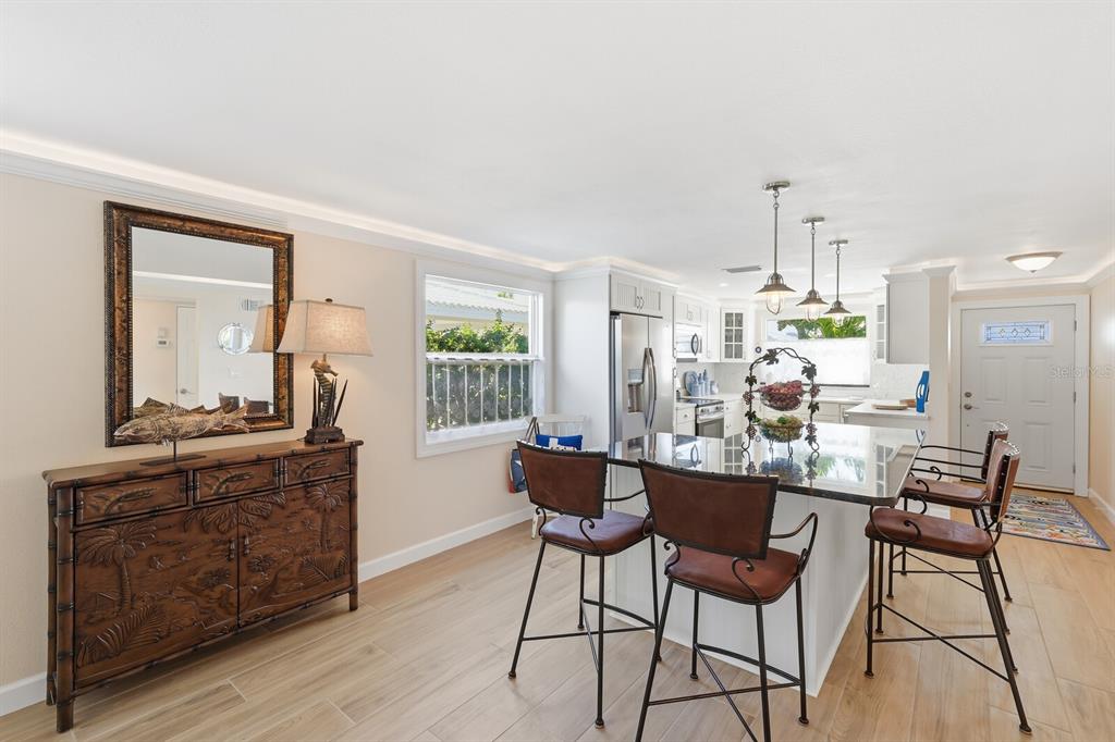 A kitchen with a central island, bar seating, light wood flooring, and a decorative wooden sideboard — 573 SPANISH DRIVE N, LONGBOAT KEY, FL
