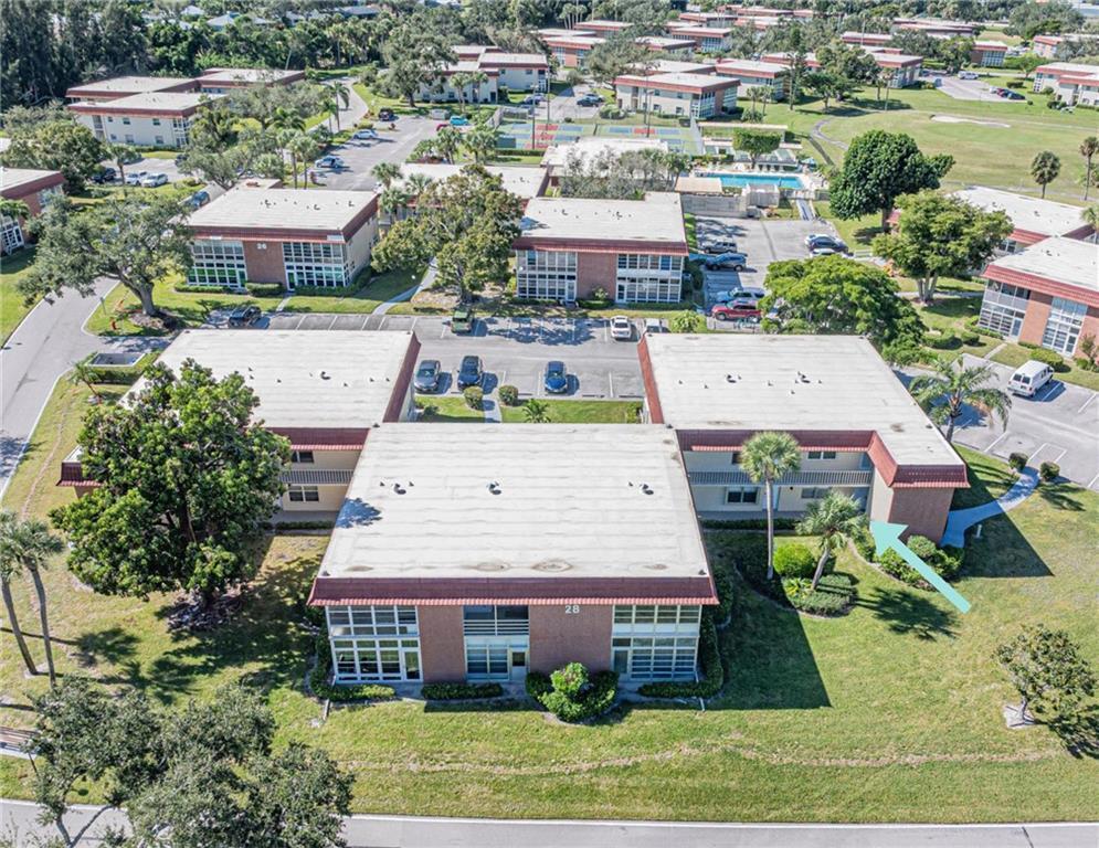 An aerial view of a multi-story apartment building with a flat roof and parking lot — 28 Pine Arbor Lane # 101, Vero Beach FL 32962, VERO BEACH, FL
