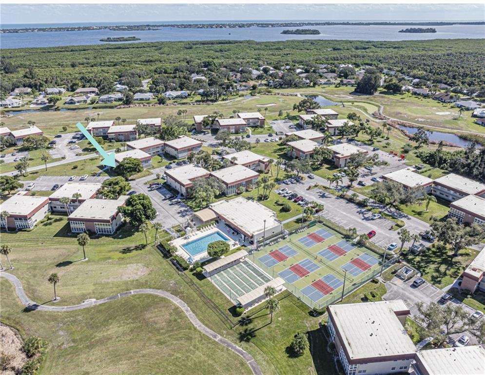 An aerial view shows a residential complex with multiple buildings, a swimming pool, and courts — 28 Pine Arbor Lane # 101, Vero Beach FL 32962, VERO BEACH, FL