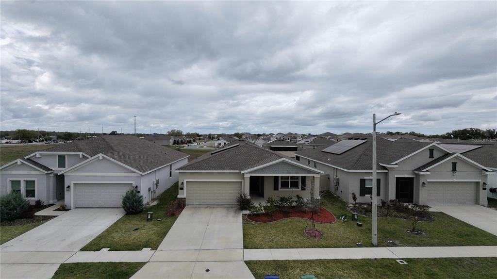 An aerial view of three suburban single-family homes with driveways and lawns under a cloudy sky — 652 GROVE STREET, WINTER HAVEN, FL
