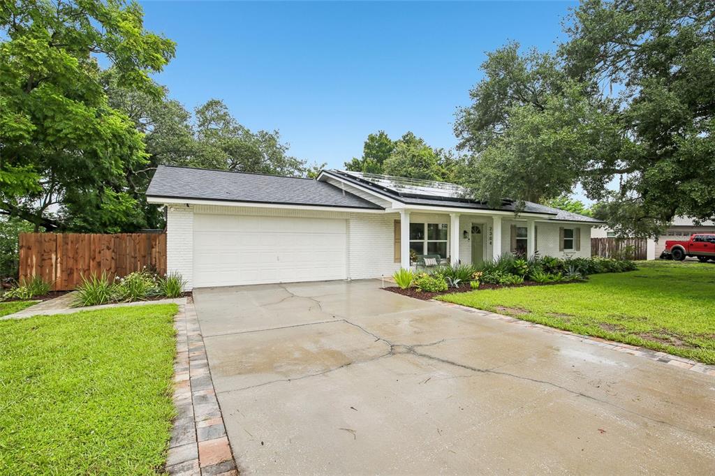 A single-story white brick house with a two-car garage and solar panels on the roof — 2304 MEDFORD LANE, BRANDON, FL