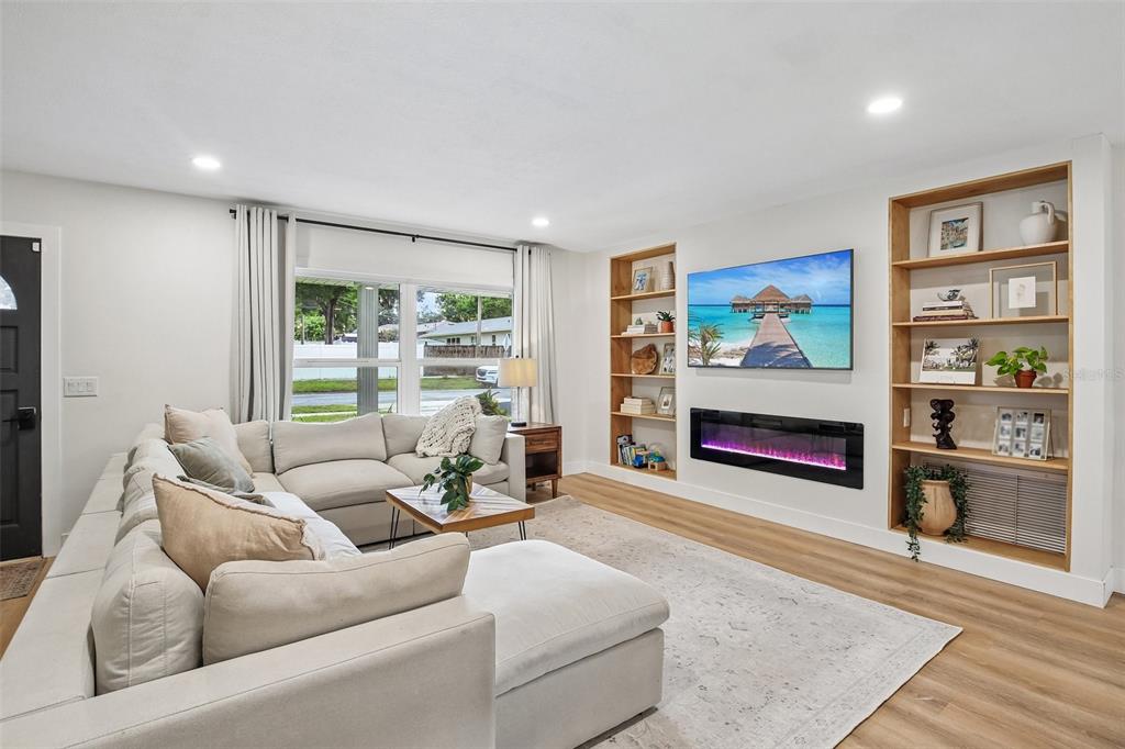 A living room features a sectional sofa, a wall-mounted television, and built-in wooden shelving — 2304 MEDFORD LANE, BRANDON, FL