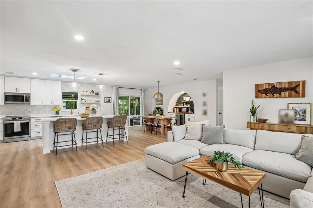 An open-concept living room and kitchen feature white cabinetry, a large island, and wood flooring — 2304 MEDFORD LANE, BRANDON, FL