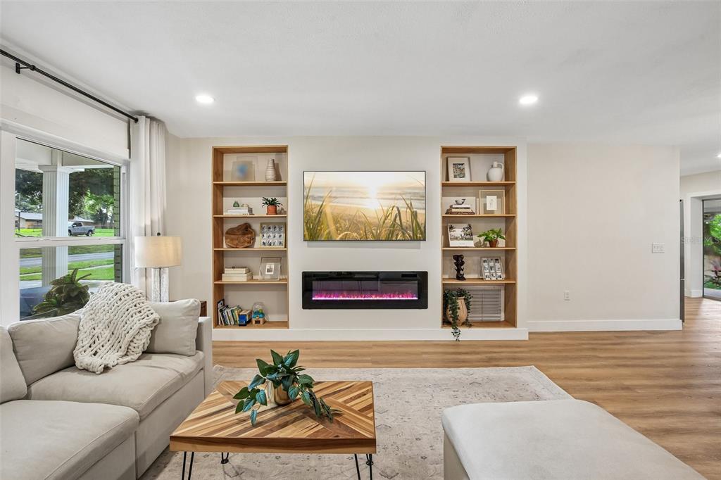 A living room features a built-in fireplace and shelving unit, a sectional sofa, and wood flooring — 2304 MEDFORD LANE, BRANDON, FL