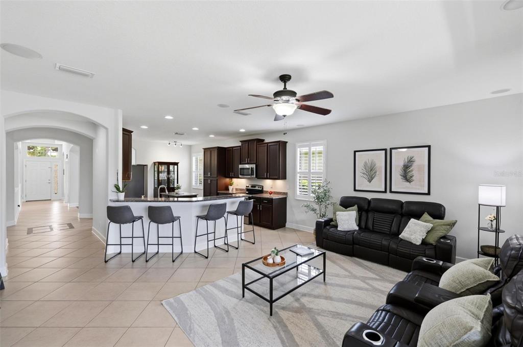 An open-concept living room and kitchen featuring dark cabinetry, a breakfast bar, and tile flooring — 2199 TERRACINA DRIVE, VENICE, FL