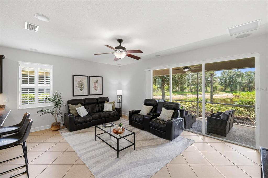 A living room with black leather furniture, a glass coffee table, and sliding glass doors — 2199 TERRACINA DRIVE, VENICE, FL