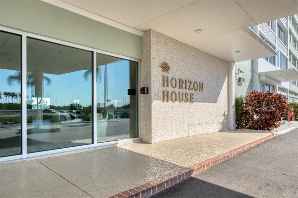 The exterior entrance of a building features a stone wall with the name Horizon House — 31 ISLAND WAY UNIT 508, CLEARWATER BEACH, FL