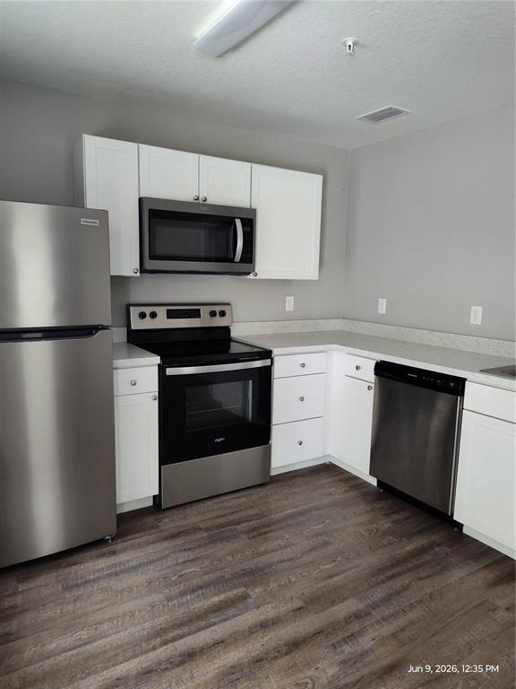 A kitchen features white cabinets, stainless steel appliances, and wood-look flooring — 5580 NE 35TH STREET, SILVER SPRINGS, FL