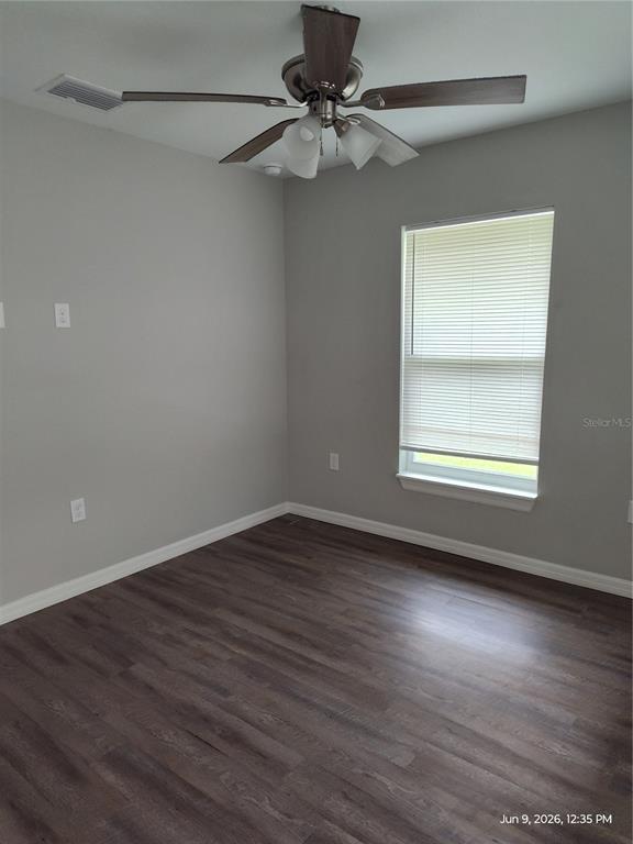 An empty bedroom features gray walls, dark wood-look flooring, a ceiling fan, and a window — 5580 NE 35TH STREET, SILVER SPRINGS, FL