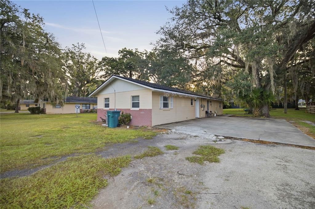 A single-story house with a concrete driveway and large oak trees in the yard — 421 NE 26TH COURT, OCALA, FL