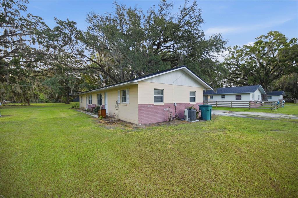 A single-story house with yellow siding and a brick base sits on a grassy lot — 421 NE 26TH COURT, OCALA, FL