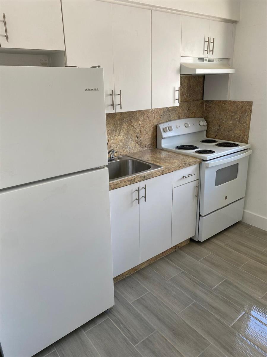 A small kitchen features white cabinets, a white refrigerator, a stove, and a sink — 460 SW 7th Street, Miami FL 33130, MIAMI, FL