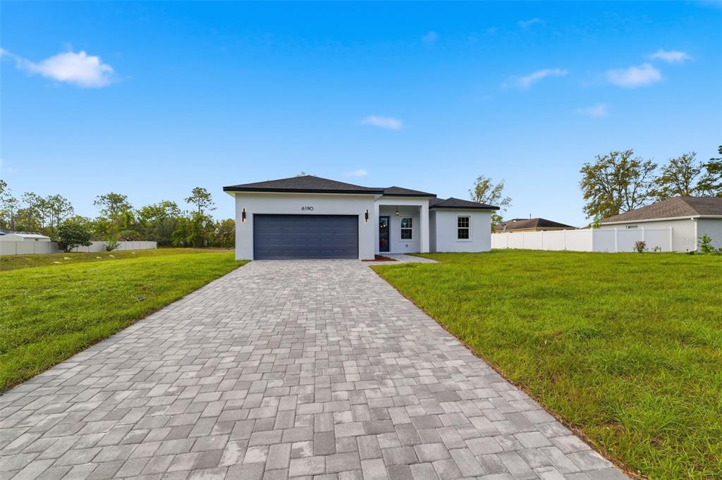 A single-story house with a paved driveway, a two-car garage, and a white exterior — 6190 SW 144TH PLACE, OCALA, FL