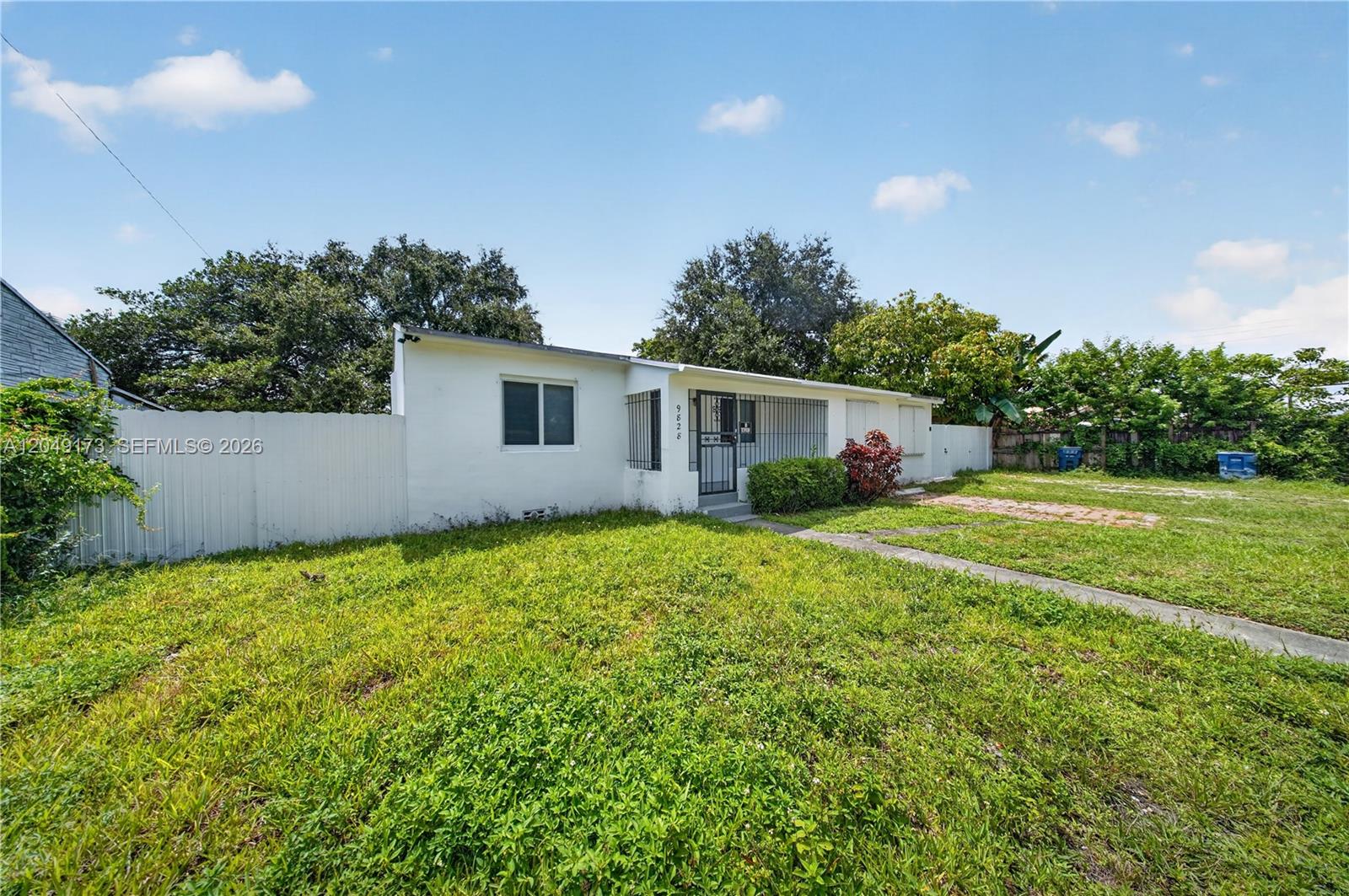 A single-story white house with a front porch and a large grassy yard — 9828 NW 26th Ave, Miami FL 33147, MIAMI, FL