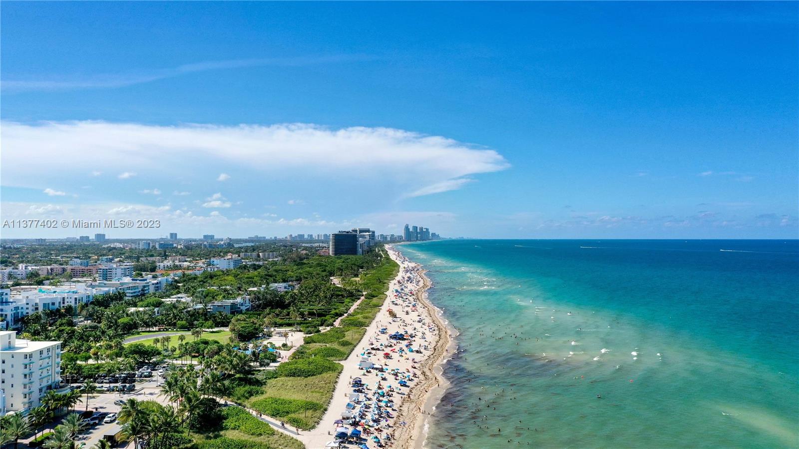 An aerial view shows a crowded beach along the ocean next to a coastal city — 7300 Ocean Ter # 110, Miami Beach FL 33141, MIAMI BEACH, FL