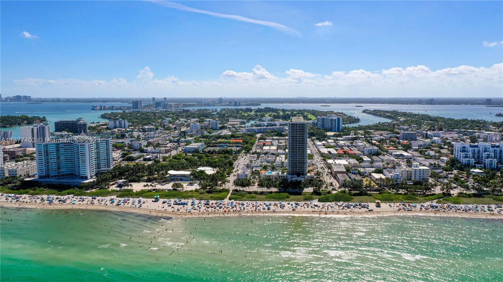 An aerial view shows a sandy beach, turquoise ocean, and high-rise buildings in a coastal city — 7300 Ocean Ter # 110, Miami Beach FL 33141, MIAMI BEACH, FL