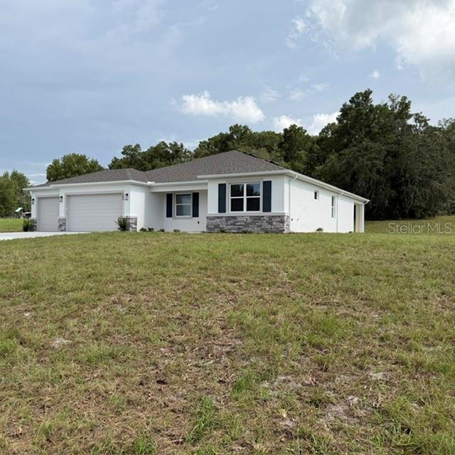 A single-story house with a white exterior, stone accents, and a three-car garage — 380 E DUSTY COURT, HERNANDO, FL