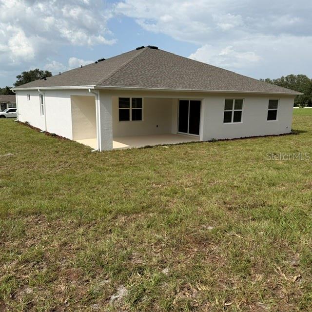 The rear exterior of a single-story house features a covered patio and a grassy yard — 380 E DUSTY COURT, HERNANDO, FL