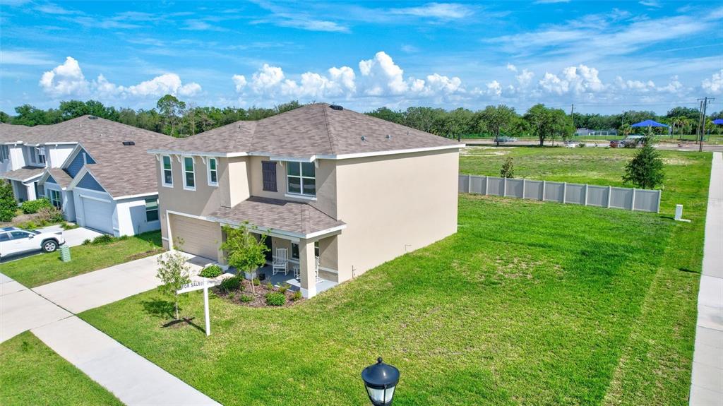 An aerial view of a two-story suburban house with a tan exterior and a large yard — 7601 ROSEWOOD GARDEN LOOP, TAMPA, FL