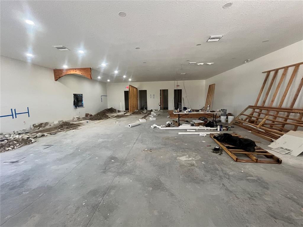 An unfinished interior space features a concrete floor, exposed framing, and scattered construction materials — 1989 21ST STREET NW, WINTER HAVEN, FL