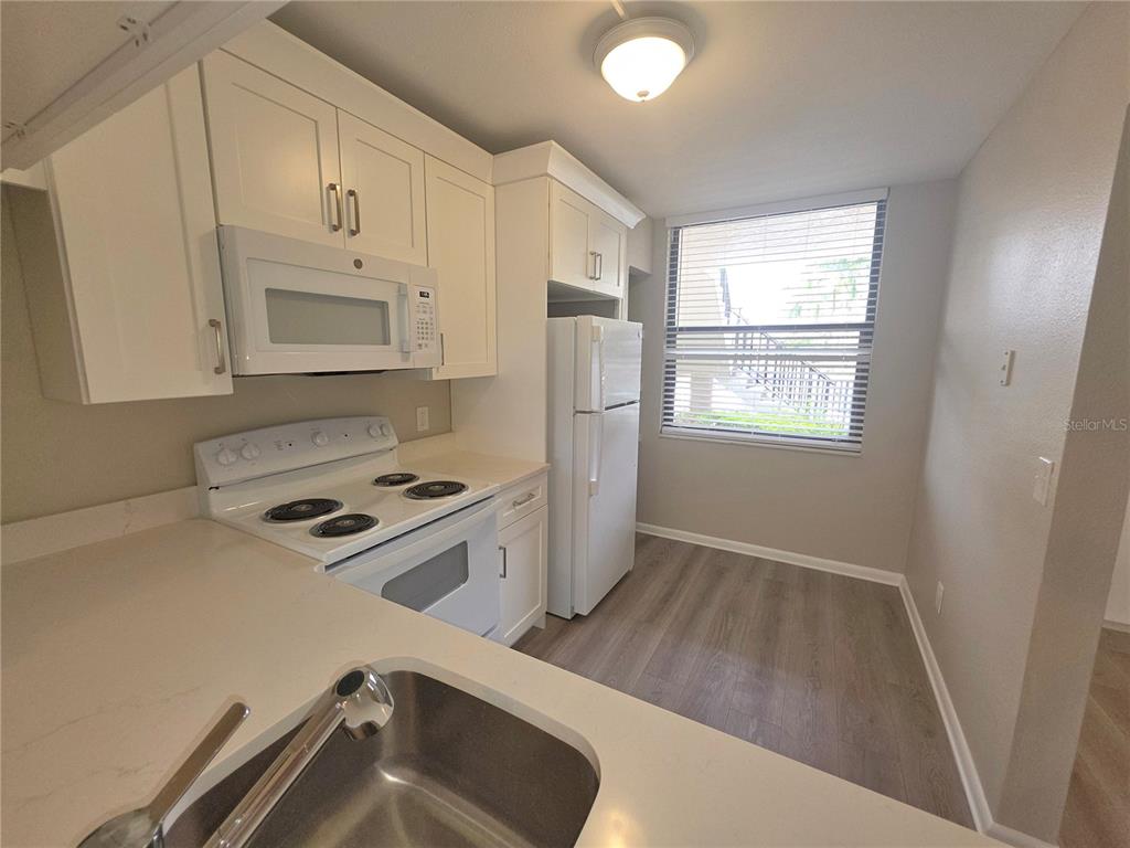 A kitchen with white cabinets, a white stove, a white refrigerator, and light wood flooring — 2049 SKIMMER COURT W UNIT 311, CLEARWATER, FL