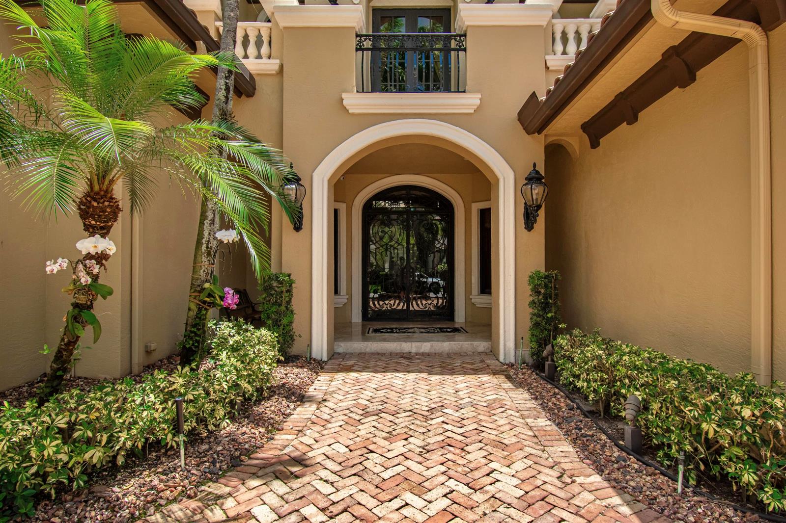 A brick walkway leads to an arched entryway with a decorative iron door and balcony — 17690 Middlebrook Way, Boca Raton FL 33496, BOCA RATON, FL