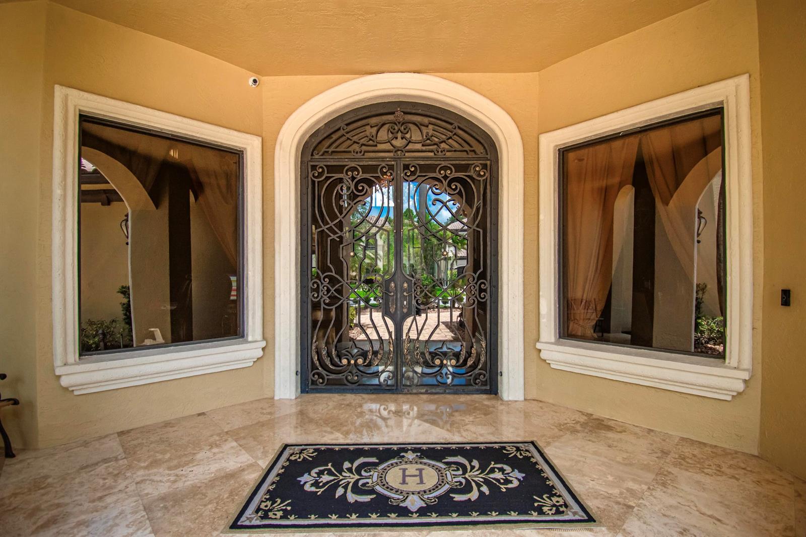 An ornate wrought iron double door entry features a stone floor and a monogrammed rug — 17690 Middlebrook Way, Boca Raton FL 33496, BOCA RATON, FL