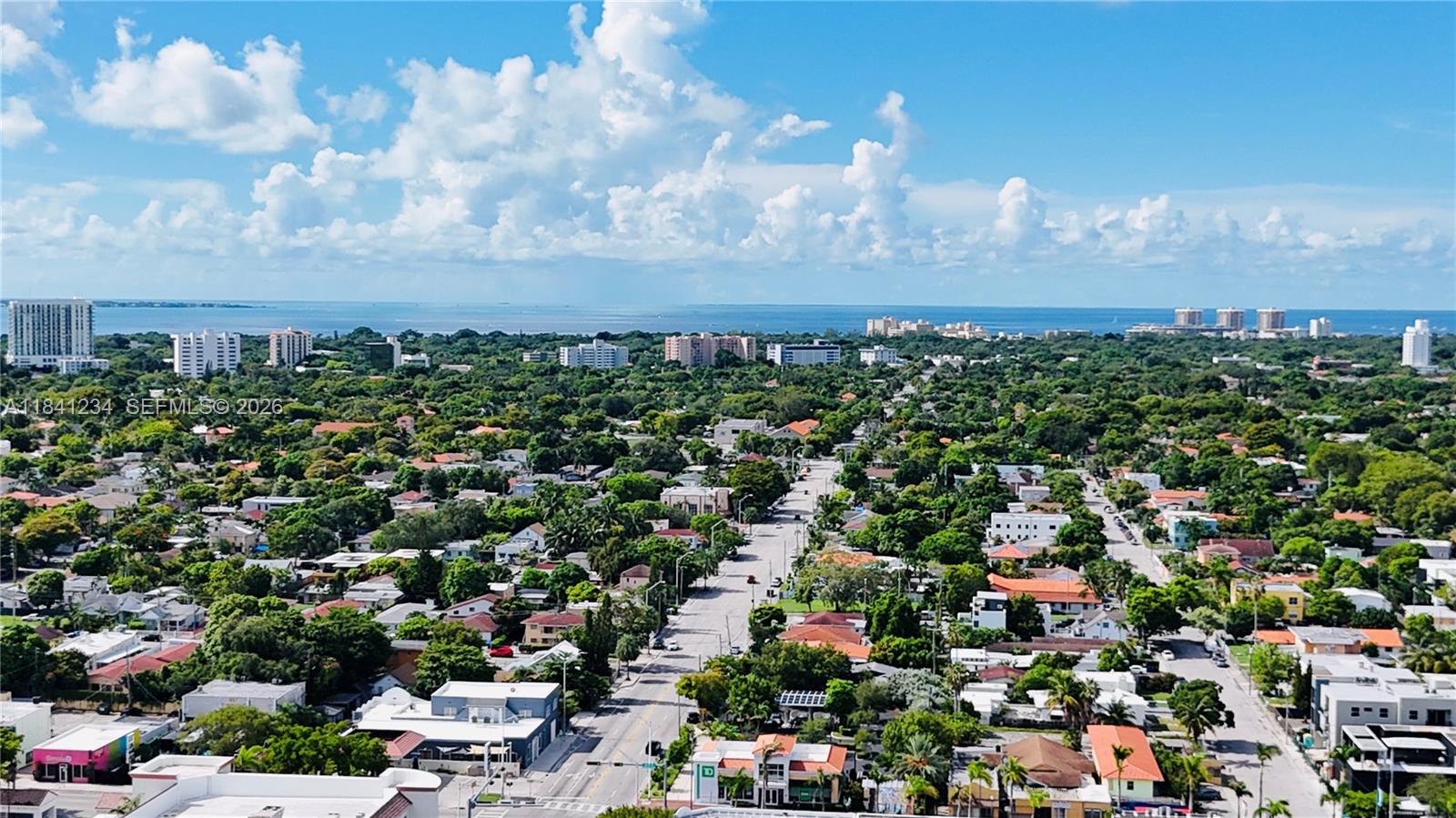 An aerial view shows a residential neighborhood with lush trees, streets, and a distant coastline — 1238 SW 4th St, Miami FL 33135, MIAMI, FL