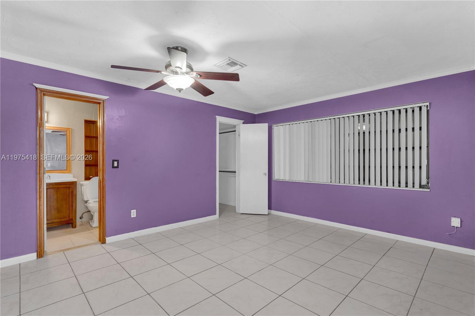 A bedroom with purple walls, tile flooring, a ceiling fan, and an attached bathroom — 16501 SW 102nd Ct, Miami FL 33157, MIAMI, FL