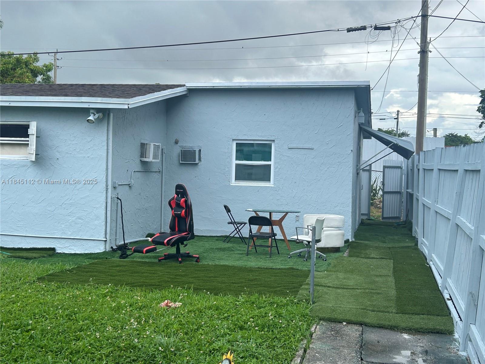 The exterior of a light blue house features a small patio area with artificial turf — 2708 NW 22nd Ct, Miami FL 33142, MIAMI, FL