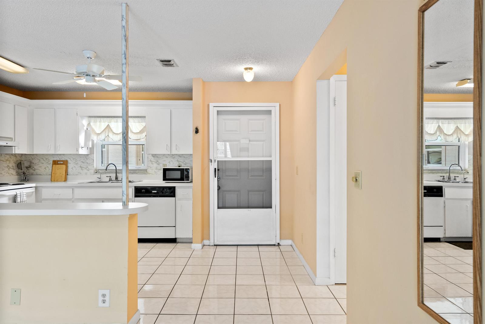 A kitchen with white cabinets, tiled floors, and a door leading to the exterior — 6531 SE Federal Highway # M112, Stuart FL 34997, STUART, FL