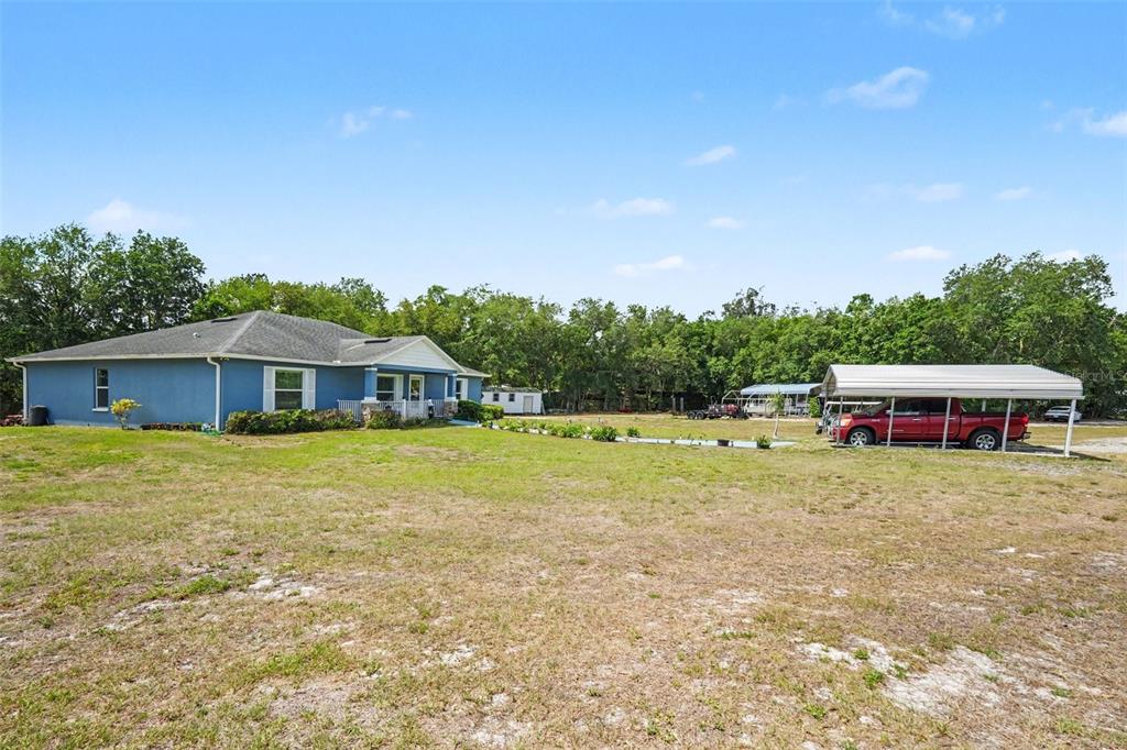 A blue house with a covered carport sits on a large, grassy lot — 3147 SYDNEY DOVER ROAD, DOVER, FL
