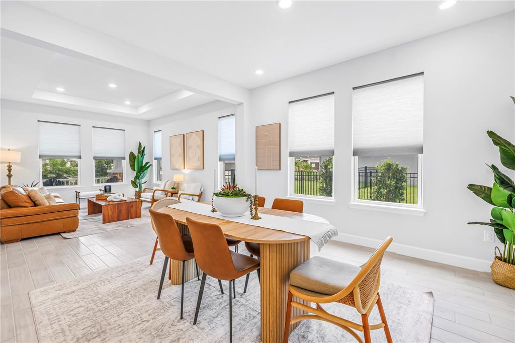 A dining area with a wooden table and chairs opens into a bright living room — 11133 FIELDSTONE DRIVE, PALMETTO, FL