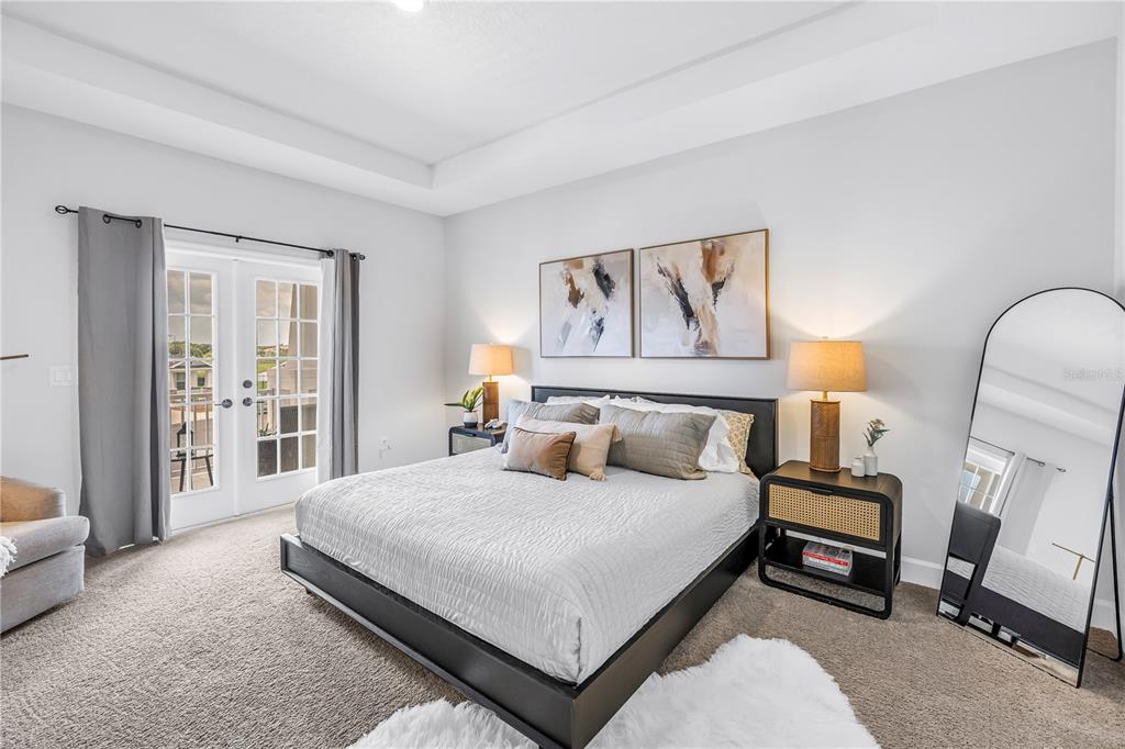 A bedroom features a platform bed, two nightstands, wall art, and glass doors to a balcony — 11133 FIELDSTONE DRIVE, PALMETTO, FL