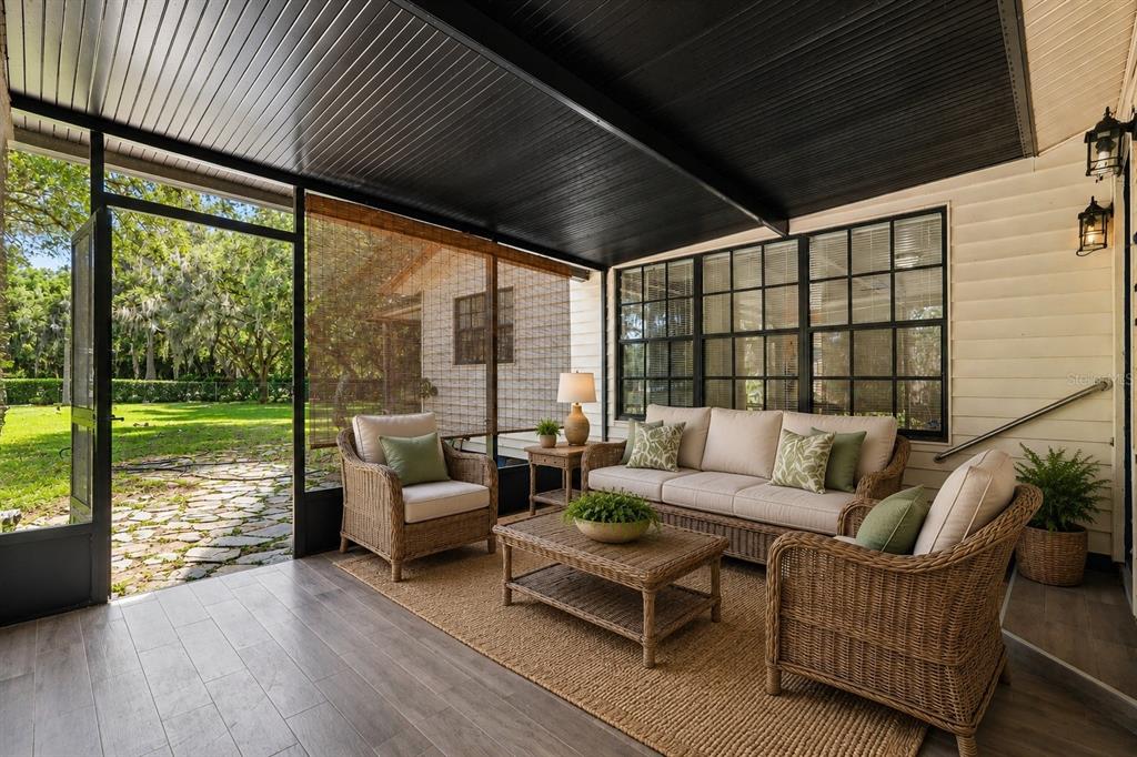 A screened-in porch features wicker furniture, a wood-look floor, and a black ceiling — 231 DUKE SIMMS ROAD, BRANDON, FL