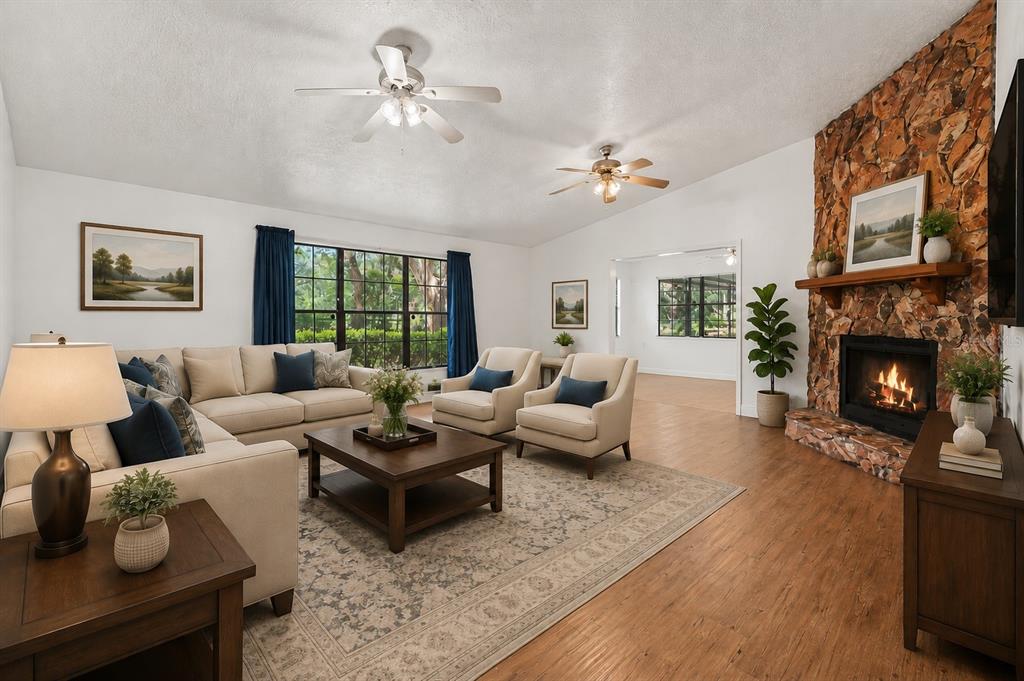 A living room features a stone fireplace, two ceiling fans, and neutral furniture on wood floors — 231 DUKE SIMMS ROAD, BRANDON, FL