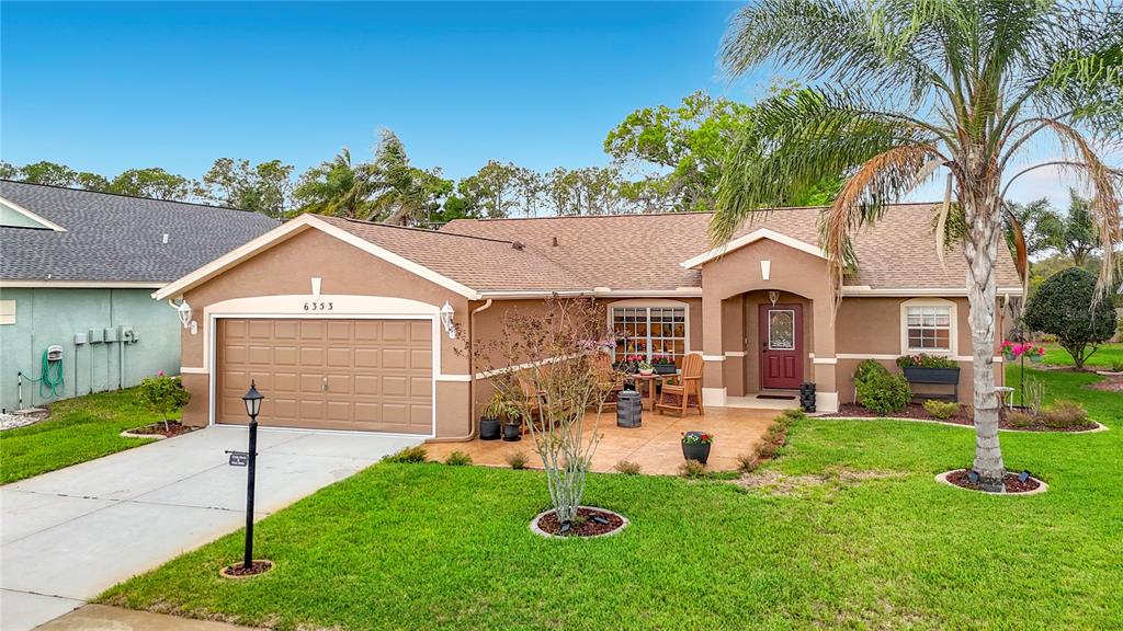 A single-story house with a brown garage, front patio, and a palm tree — 6353 CARDINAL CREST DRIVE, NEW PORT RICHEY, FL